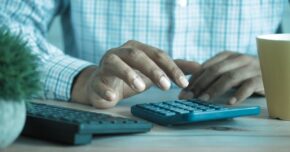Man typing into calculator - DIR fees hangover